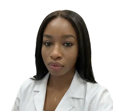 A woman with long black hair wearing a brown jacket stands confidently, showcasing her style and poise.