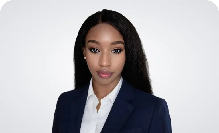 A woman with long black hair wearing a brown jacket stands confidently, showcasing her style and poise.