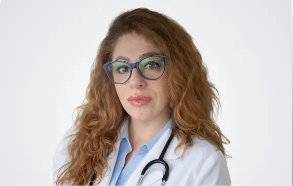 A woman wearing a white coat and glasses stands confidently, showcasing a professional appearance.